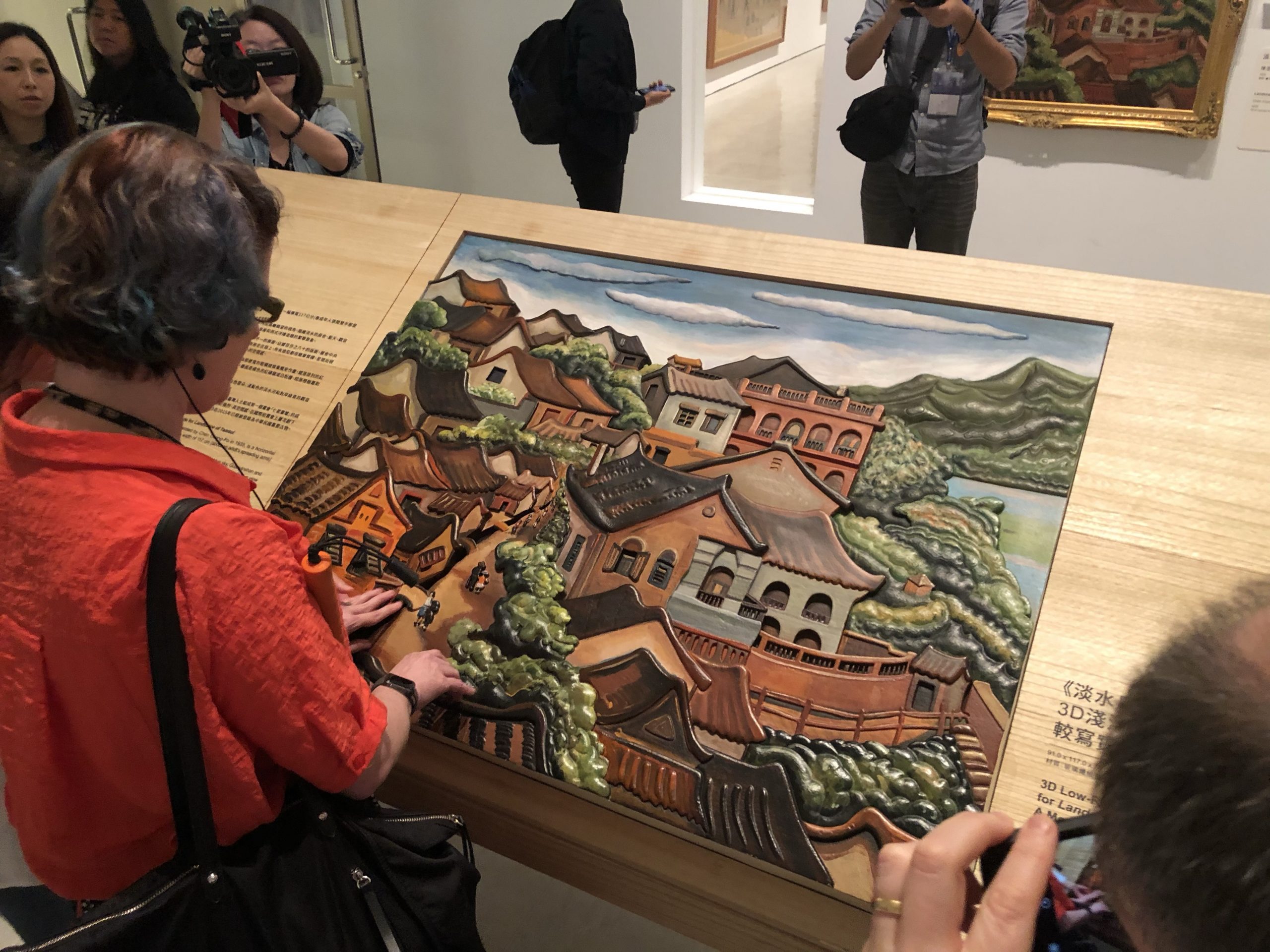 A woman uses her hands to touch a tactile rendering of a painting